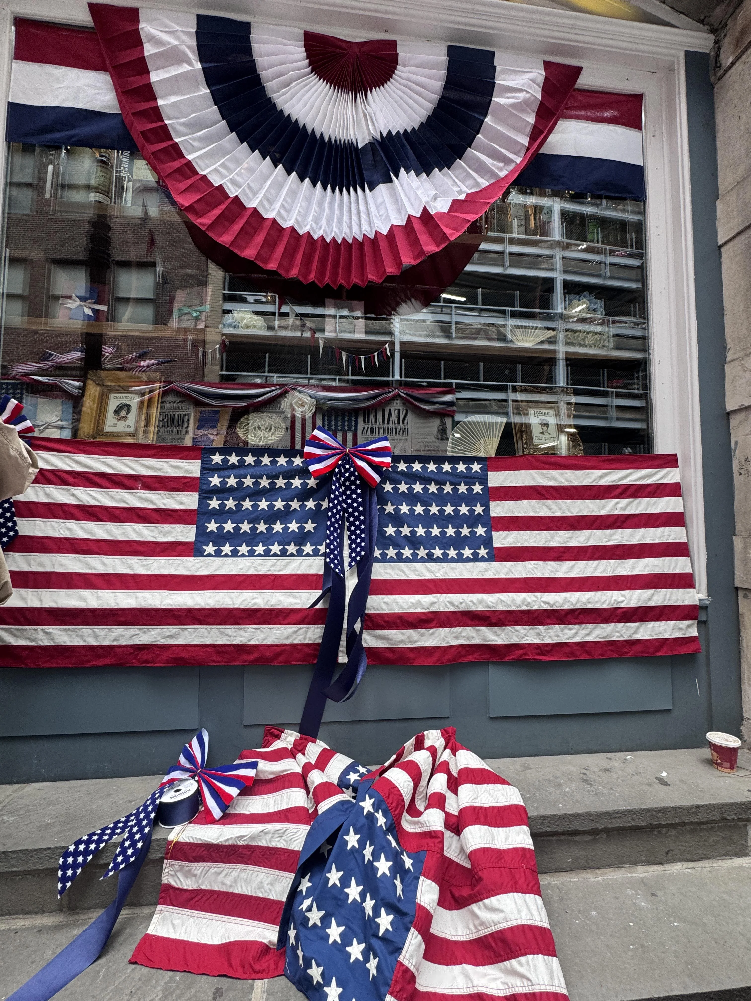 Close-up of patriotic set dressing — period-correct 38-star American flags and red-white-blue bunting rosettes